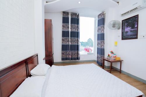 a bedroom with a large bed and a window at Triệu Vũ Hotel & Apartment in Buon Ma Thuot