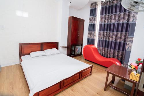 a bedroom with a bed and a red chair at Triệu Vũ Hotel & Apartment in Buon Ma Thuot