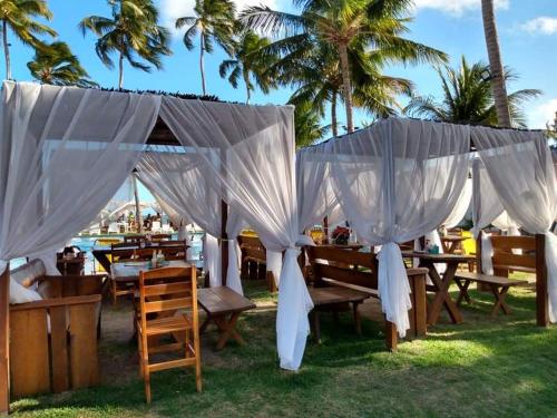 un gruppo di tavoli con tende bianche sull'erba di Apart Verdemar Confort com 3 quartos para ate 8 pessoas moderno e funcional e apenas poucos passos da praia a Maceió
