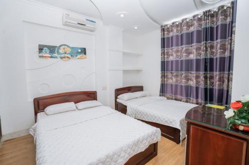 a room with two beds and a glass table at Triệu Vũ Hotel & Apartment in Buon Ma Thuot