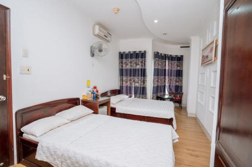 a bedroom with two beds and a desk and a table at Triệu Vũ Hotel & Apartment in Buon Ma Thuot