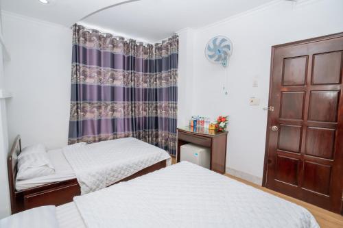 a bedroom with two beds and a curtain at Triệu Vũ Hotel & Apartment in Buon Ma Thuot