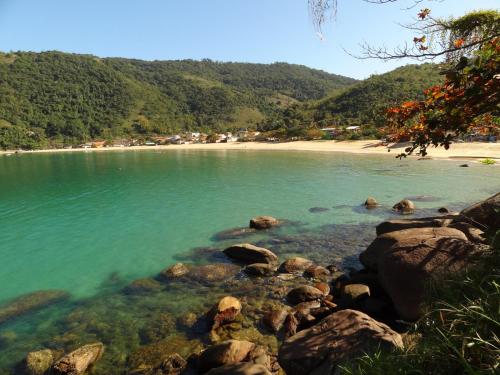 a body of water with rocks and a beach at Suite Baia dos Corais in Angra dos Reis