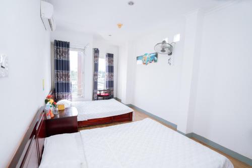 a bedroom with two beds and a window at Triệu Vũ Hotel & Apartment in Buon Ma Thuot