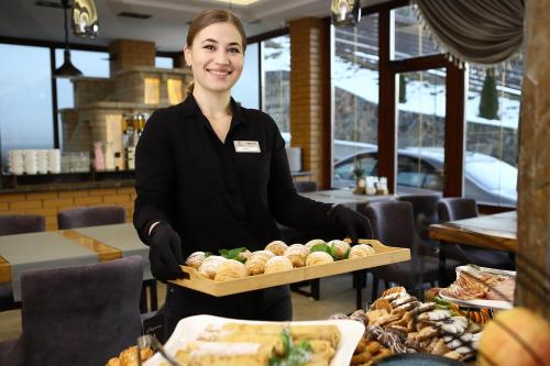 a woman holding a tray of food in a restaurant at Hotel Podgorie Spa in Bukovel