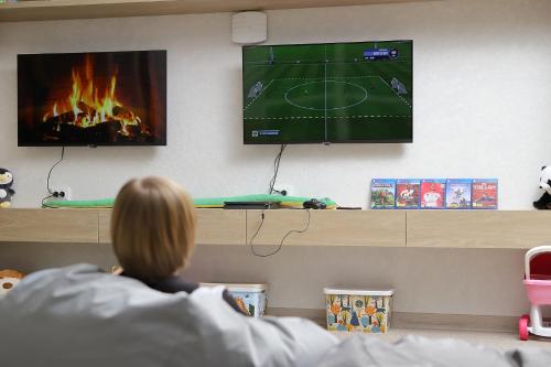 a person laying in bed watching a tv with a fire at Hotel Podgorie Spa in Bukovel