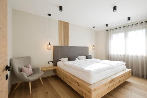 1 dormitorio con 1 cama grande y 1 silla en Boutique Hotel Wiesenhof - Adults Only, en Lana