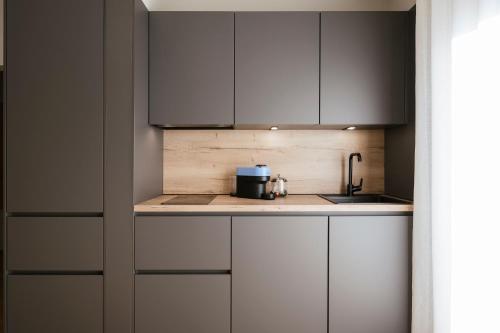 a kitchen with white cabinets and a sink at Boutique Hotel Wiesenhof - Adults Only in Lana