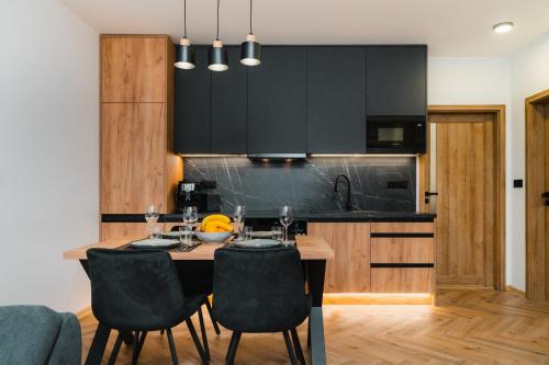 Liptovská TepláにあるLiptouka Apartmanのキッチン(木製テーブル、黒いキャビネット付)