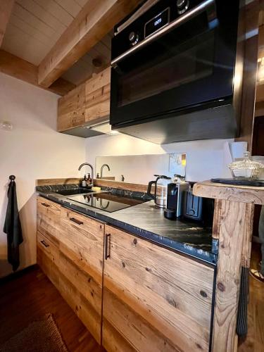 une cuisine avec des armoires en bois et un four à plaques de cuisson dans l'établissement Appartement ensoleillé aux Tines, vue Massif, à Chamonix-Mont-Blanc
