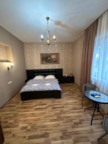 ein Schlafzimmer mit einem Bett, einem Tisch und einem Kronleuchter in der Unterkunft Hotel M.Classic in Tbilisi City