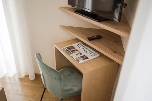 a room with a chair and a tv and a newspaper at Boutique Hotel Wiesenhof - Adults Only in Lana