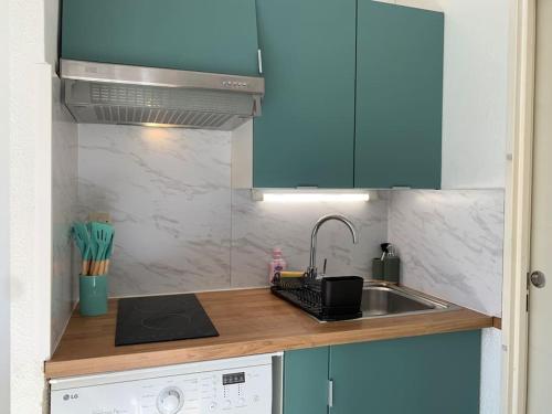 a kitchen with blue cabinets and a sink at Maisonnette dans belle résidence in Saint-Vallier-de-Thiey