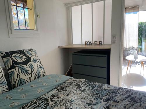 a bedroom with a bed and a table and a window at Maisonnette dans belle résidence in Saint-Vallier-de-Thiey