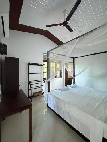 a bedroom with a white bed with a ceiling fan at Tanzanite place in Tangalle
