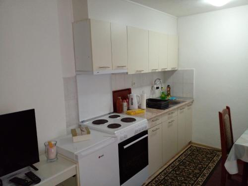 a small kitchen with a stove and white cabinets at Stan na dan Apartman Kozarac in Kozarac