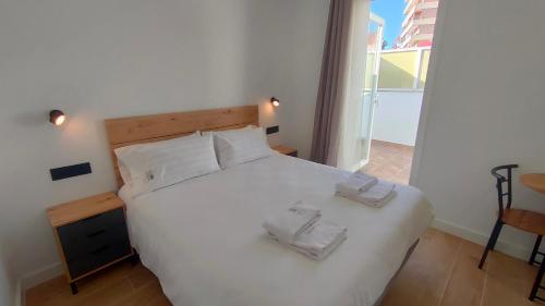 um quarto com uma cama branca com duas toalhas em MiRa San Basilio em Córdoba
