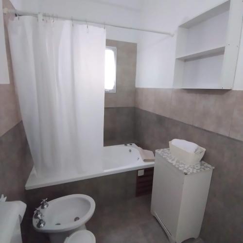 a bathroom with a toilet and a tub and a sink at Acacia in Pinamar