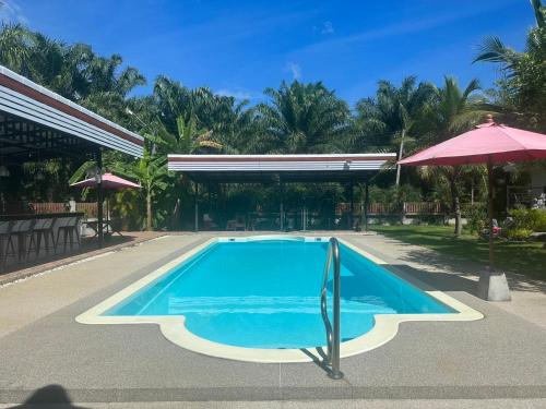 - une piscine dans un complexe avec un parasol dans l'établissement อิงแลนด์เฮ้าส์แอนด์พูล England8House&Pool, à Khanom