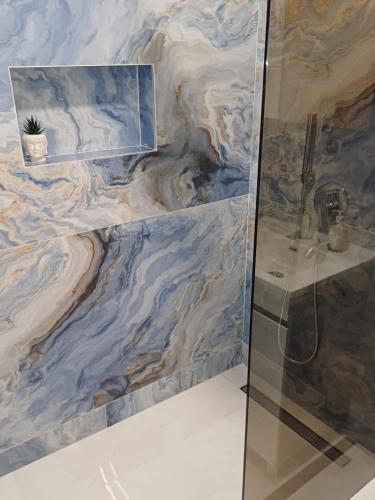 y baño con ducha y pared de mármol. en Villa Sweet Dreams en Novi Sad