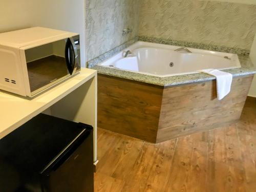 a bath tub in a kitchen with a microwave at Hotel Pousada Riacho da Areia in Águas de Lindóia