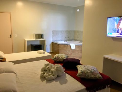 a room with two beds and a bath tub at Hotel Pousada Riacho da Areia in Águas de Lindóia
