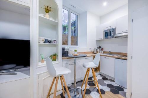 une cuisine avec des placards blancs, une table et des tabourets dans l'établissement Charmant appartement à deux pas du Vieux-Port, à La Rochelle