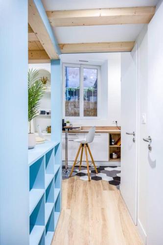 Elle comprend une cuisine avec des murs bleus et blancs et un bureau. dans l'établissement Charmant appartement à deux pas du Vieux-Port, à La Rochelle