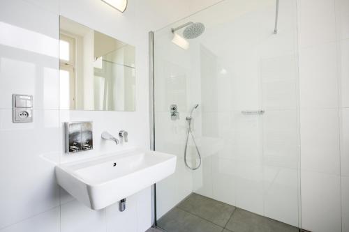 a white bathroom with a sink and a shower at Sophie's Hostel in Prague