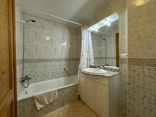 uma casa de banho com um lavatório, uma banheira e um espelho. em Piso en el centro con vistas al mar y balcón em Roses