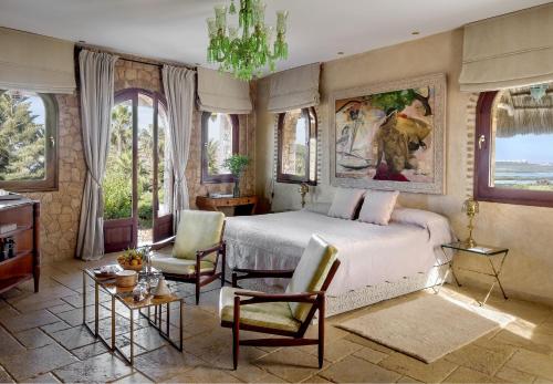 a bedroom with a bed and a chandelier and windows at La Sultana Oualidia in Oualidia