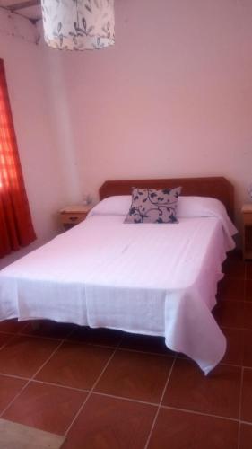a bedroom with a bed with white sheets and pillows at Arriba y La escondida in Villa Gesell