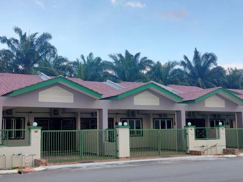 une maison avec une clôture verte devant elle dans l'établissement Homestay Fayyadh Teluk Intan 3Room2Bath, à Teluk Intan