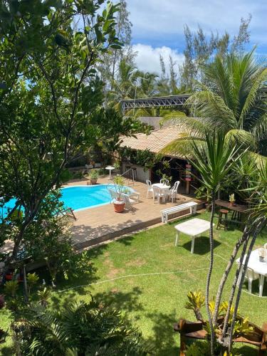 un patio trasero con piscina, mesa y sillas en Cantinho dos Machados en Camaçari