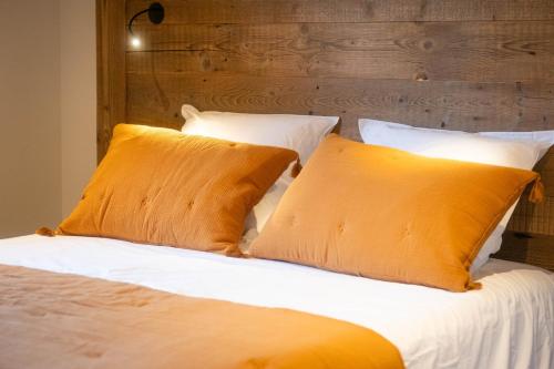 uma cama com duas almofadas cor-de-laranja e uma cabeceira em madeira em Laltizoard em Briançon