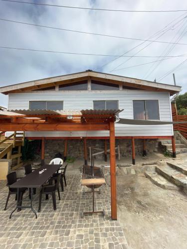 ein Haus mit einem Tisch und Stühlen davor in der Unterkunft Casa Caleta Vieja Pichidangui in Los Vilos
