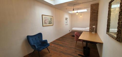 Zimmer mit einem blauen Stuhl, einem Schreibtisch und einem Bett in der Unterkunft Helles Zimmer im Loft in Mannheim