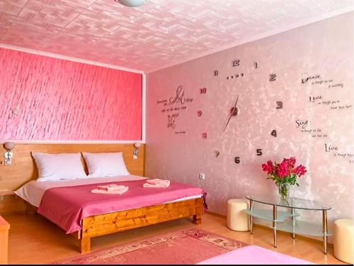 a pink bedroom with a bed and a vase of flowers at Villa Saturea in Boljevac