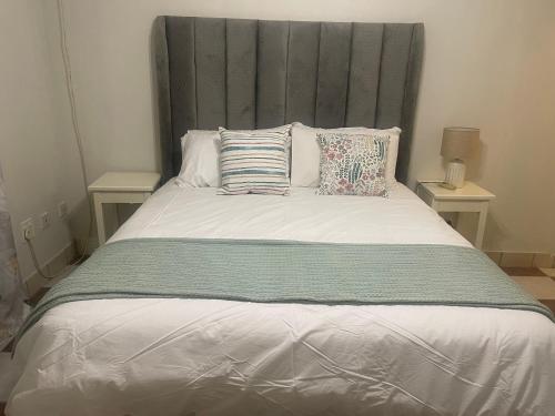Una cama con cabecero gris y almohadas. en Melrose place, en Francistown