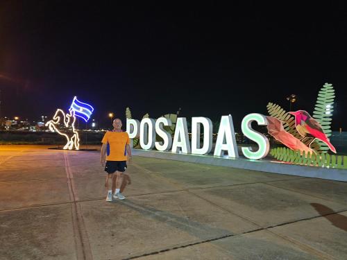a man standing in front of a sign at night at Hotel Los Chow Chow in Posadas