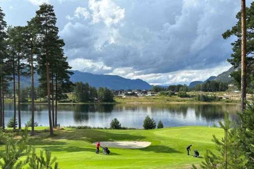 a group of people on a golf course next to a lake at Lakefront Villa, exclusive leisure property near Vrådal Golf, Straand Summerland & Panorama Ski center in Vradal