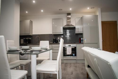a kitchen with white chairs and a table with a dining room at Exquisite 2-Bedroom City Centre Haven - Leicester's Premier Urban Retreat in Leicester