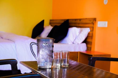 a table with two glasses on a table with a bed at JMT Eco-Binsar by StayApart in Panuānaula