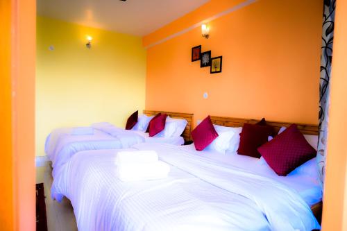 a bedroom with two beds with white sheets and red pillows at JMT Eco-Binsar by StayApart in Panuānaula