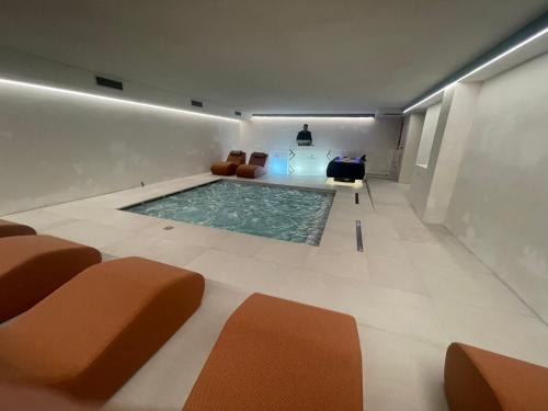 a swimming pool in a room with chairs and a table at Hotel Dahu in Madonna di Campiglio