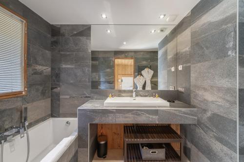 un bagno con lavandino e vasca da bagno di Chalet Kashmir 5MIN des pistes en voiture parking privé, spa, sauna a Les Allues
