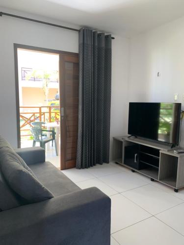 a living room with a couch and a flat screen tv at Flat Barra do Cunhaú in Canguaretama