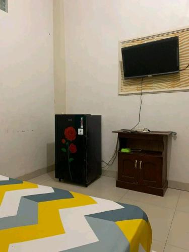 a bedroom with a television and a bed and a table at Pondok Kost Aurel 