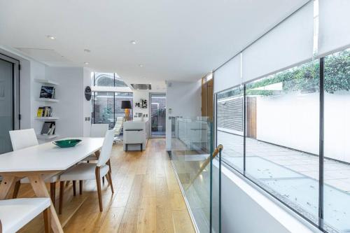 倫敦的住宿－Stylish house with superb space，一间设有玻璃墙和桌椅的用餐室