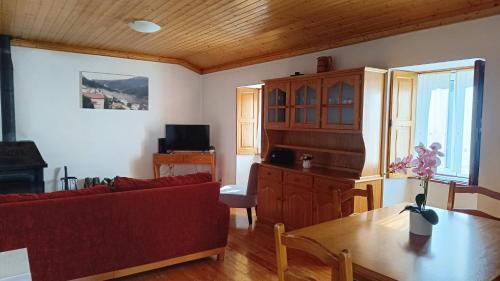 ein Wohnzimmer mit einem roten Sofa und einem Tisch in der Unterkunft Casa do Galvão -Turismo Rural - Serra da Estrela in Aguincho